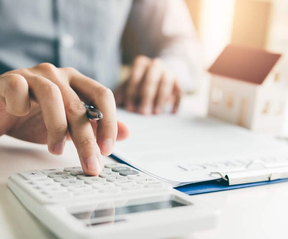 Home agents are using a calculator to calculate the loan period each month for the customer.