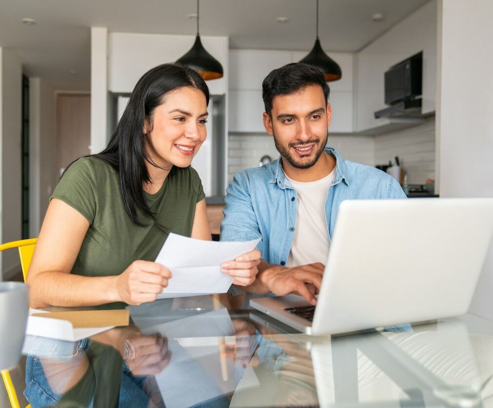 Happy couple using their laptop at home