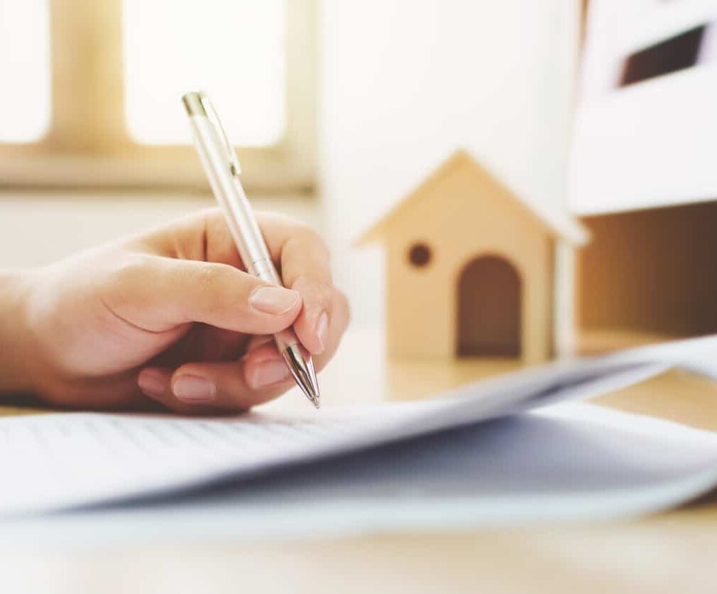 Close up hand of man signing signature loan document to home ownership